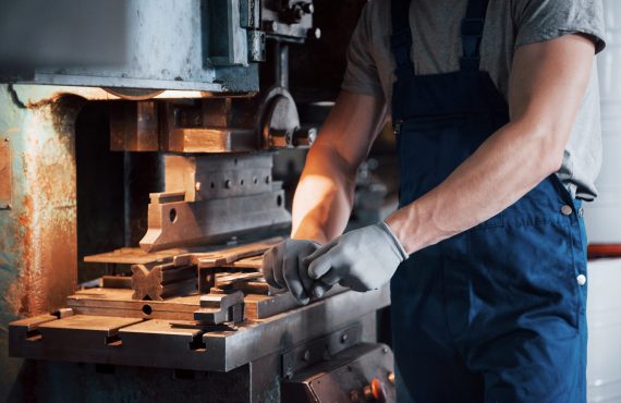 Portrait of a young worker in a hard hat at a large metalworking plant. The engineer serves the machines and manufactures parts for gas equipment.